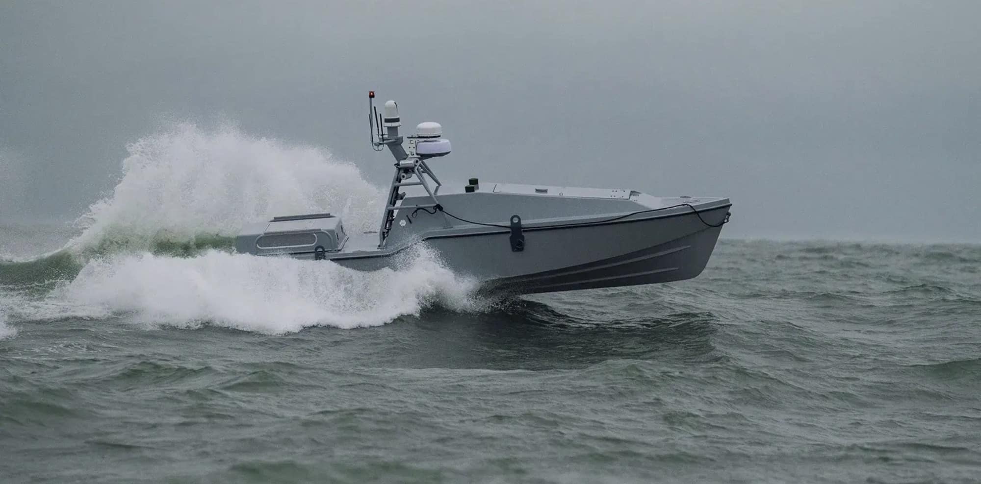 Uncrewed surface vessel powering through choppy grey seas.
