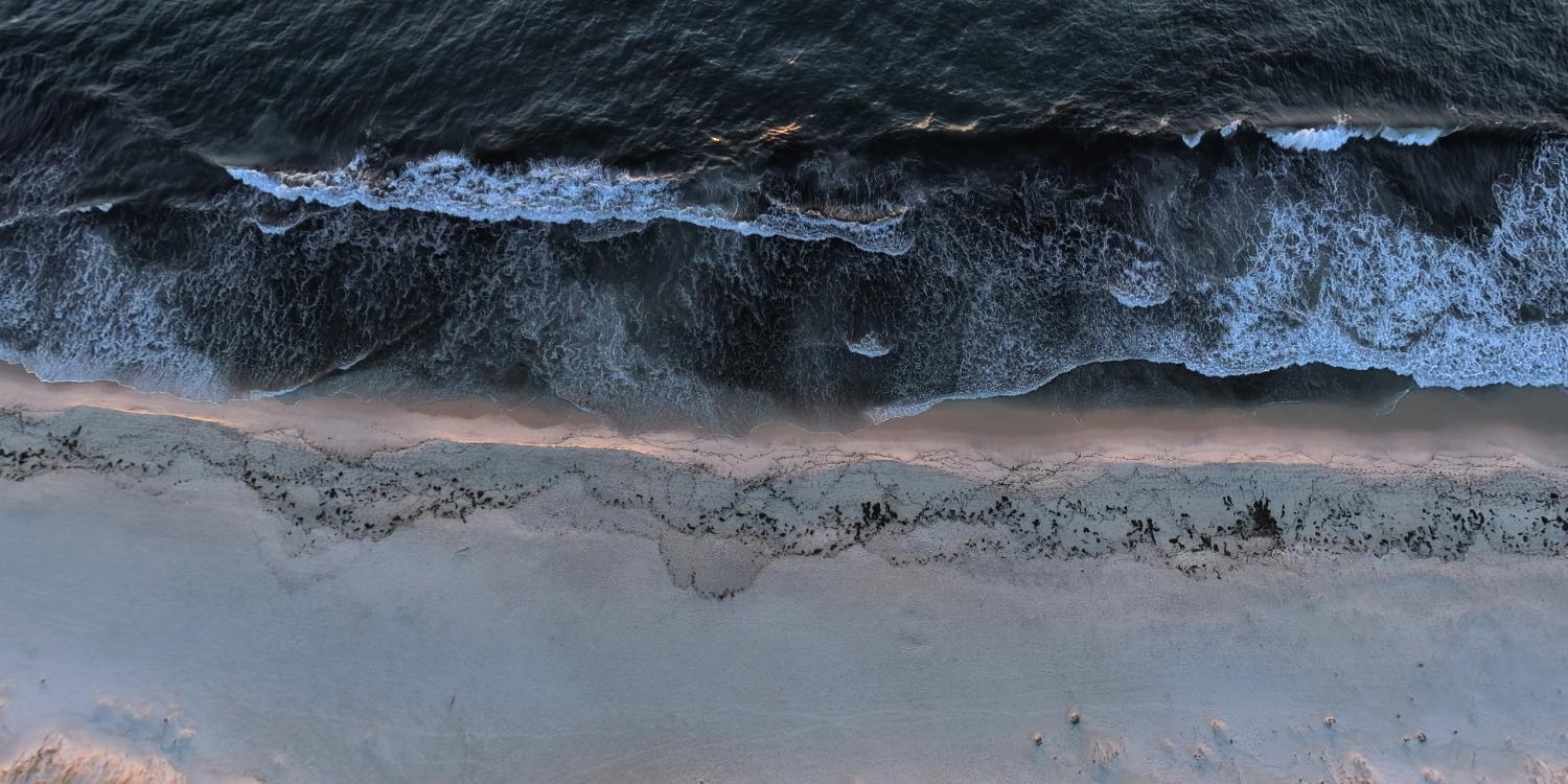 Top-down aerial view of waves breaking onto a beach captured by DJI Avata 360