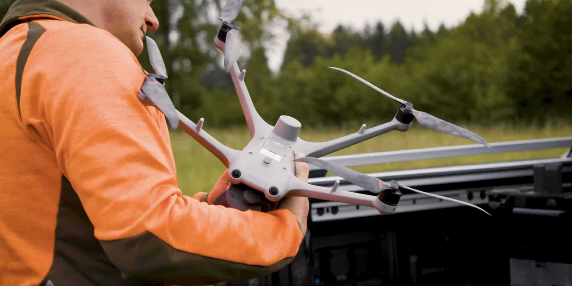 Volunteer in an orange sweater lifts a DJI Matrice 4 drone from a truck bed.
