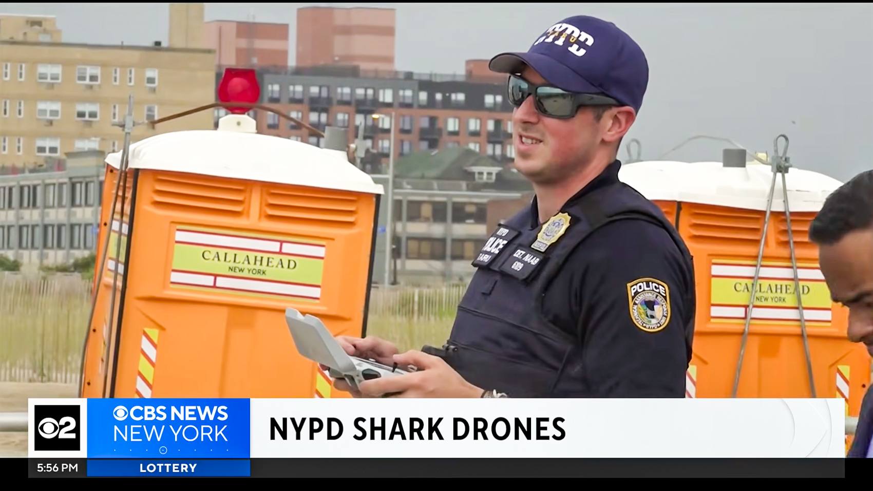 An NYPD officer holding a drone controller at Rockaway Beach