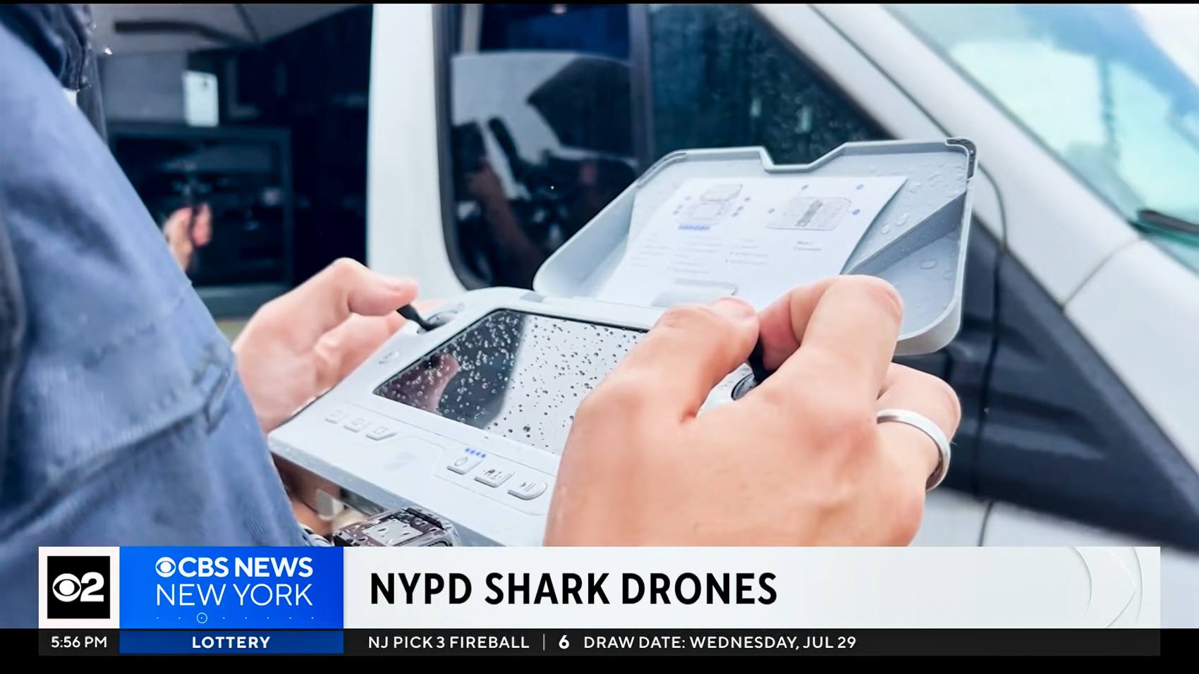 Close view of an NYPD officer's rain-speckled drone controller beside a vehicle