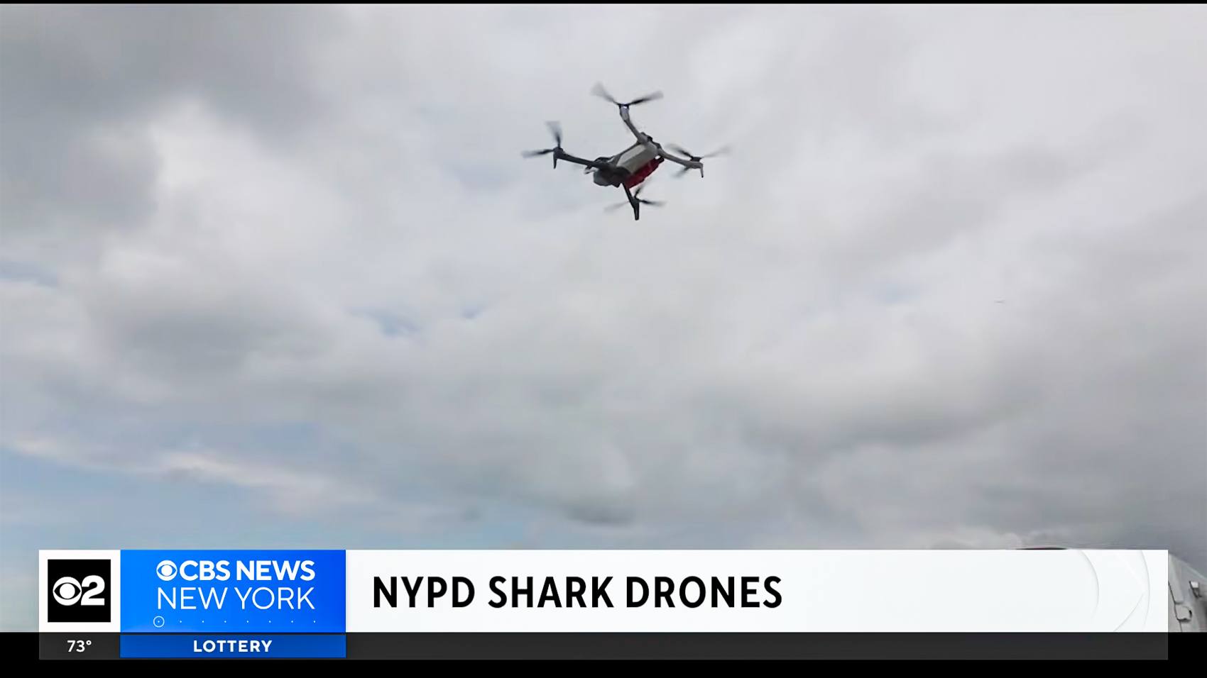 An NYPD quadcopter flying against a cloudy sky during a beach patrol