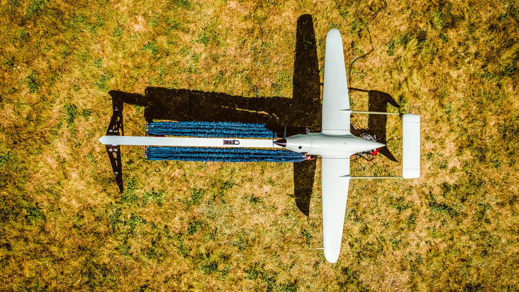 Overhead view of a Skyeton Raybird drone mounted on its launch catapult in a field