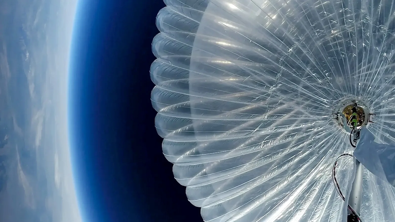 A Loon stratospheric internet balloon inflated at altitude, its translucent envelope filling the frame with the curve of the Earth visible behind it