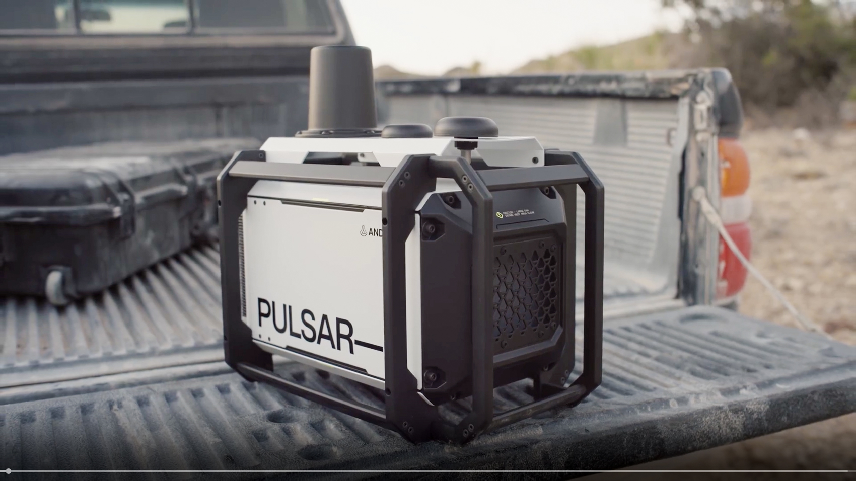 A black Pulsar radio frequency sensor unit in a protective frame sits on the bed of a pickup truck.