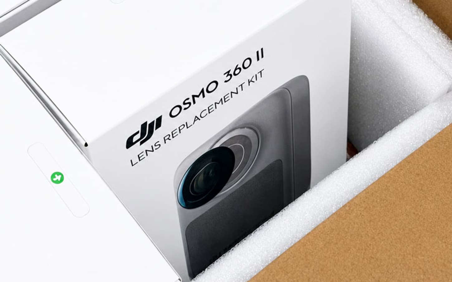 A white retail box printed DJI Osmo 360 II Lens Replacement Kit sitting in protective foam inside an opened shipping carton