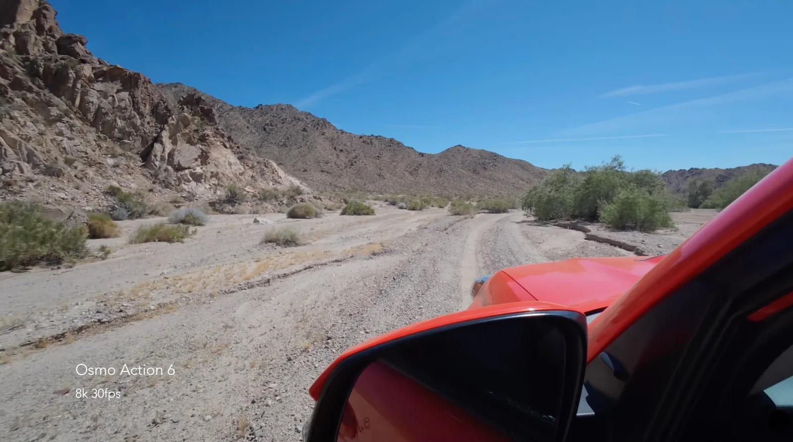 DJI Osmo Action 6 8K sample frame shot from the hood of an orange car on a sandy desert trail flanked by rocky mountains