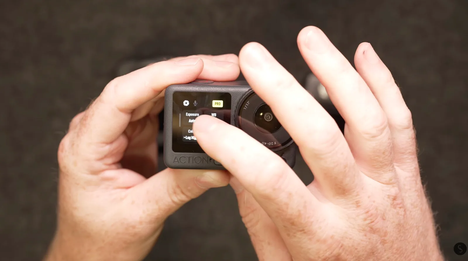 Hands holding a DJI Osmo Action camera and tapping the Pro mode exposure and white balance settings on its touchscreen