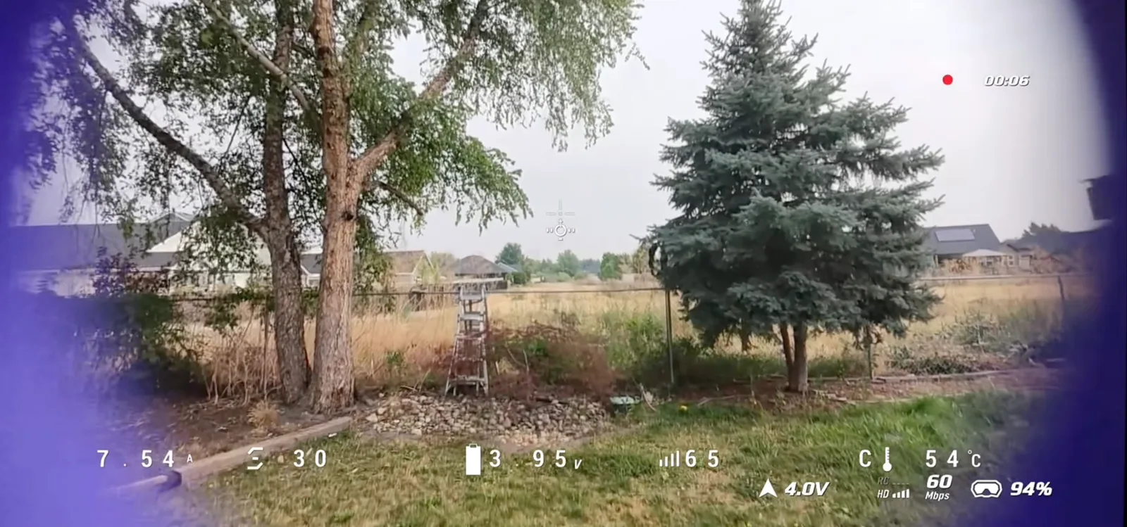 FPV goggles view showing a drone hovering low over a suburban backyard with telemetry overlay
