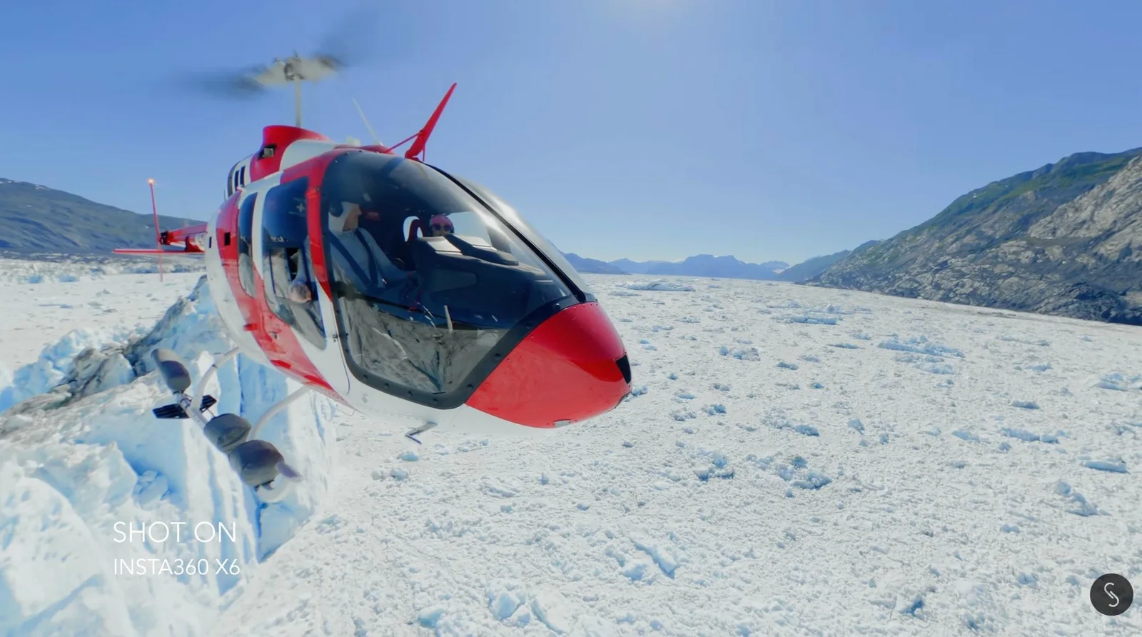 Red and white helicopter parked on a glacier with mountains behind it, captured with an Insta360 X6 360-degree camera