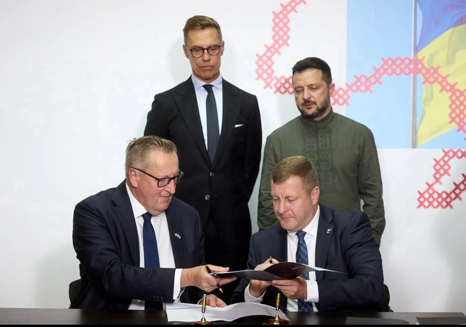 Patria CEO Panu Routila and General Cherry co-founder Stanislav Gryshyn signing documents with Alexander Stubb and Volodymyr Zelensky standing behind them