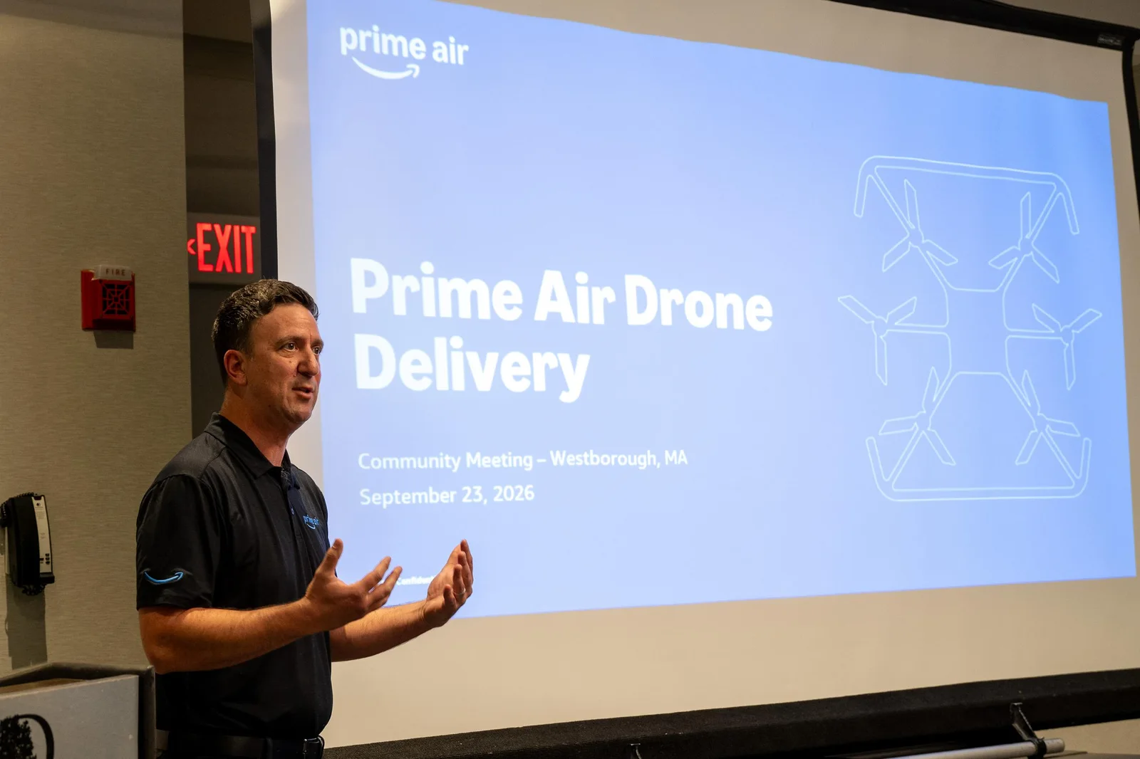 Amazon presenter speaking in front of a Prime Air Drone Delivery title slide at the Westborough, MA community meeting