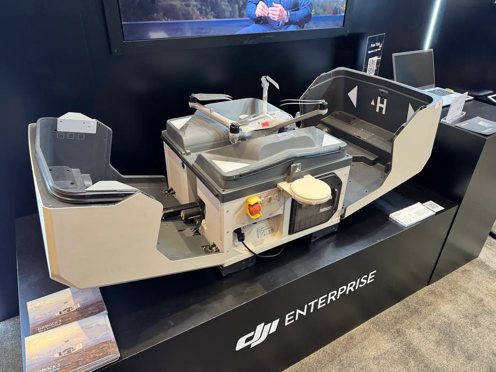 DJI Dock 3 with its lid open and a drone inside, displayed beneath a DJI Enterprise sign at a trade show booth