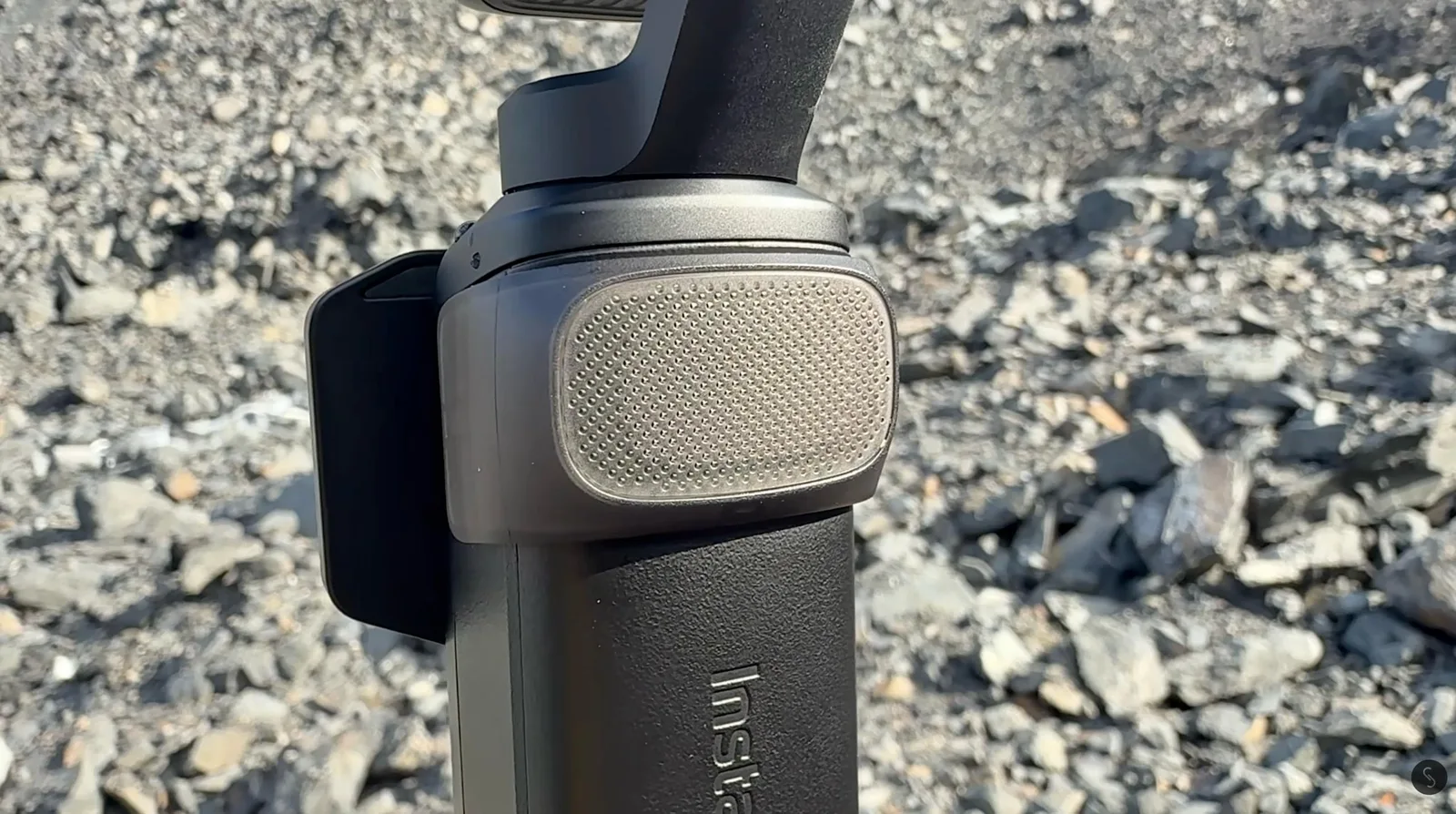 Close-up of the Insta360 Luna Pro single-lens camera head mounted on a pole over rocky terrain