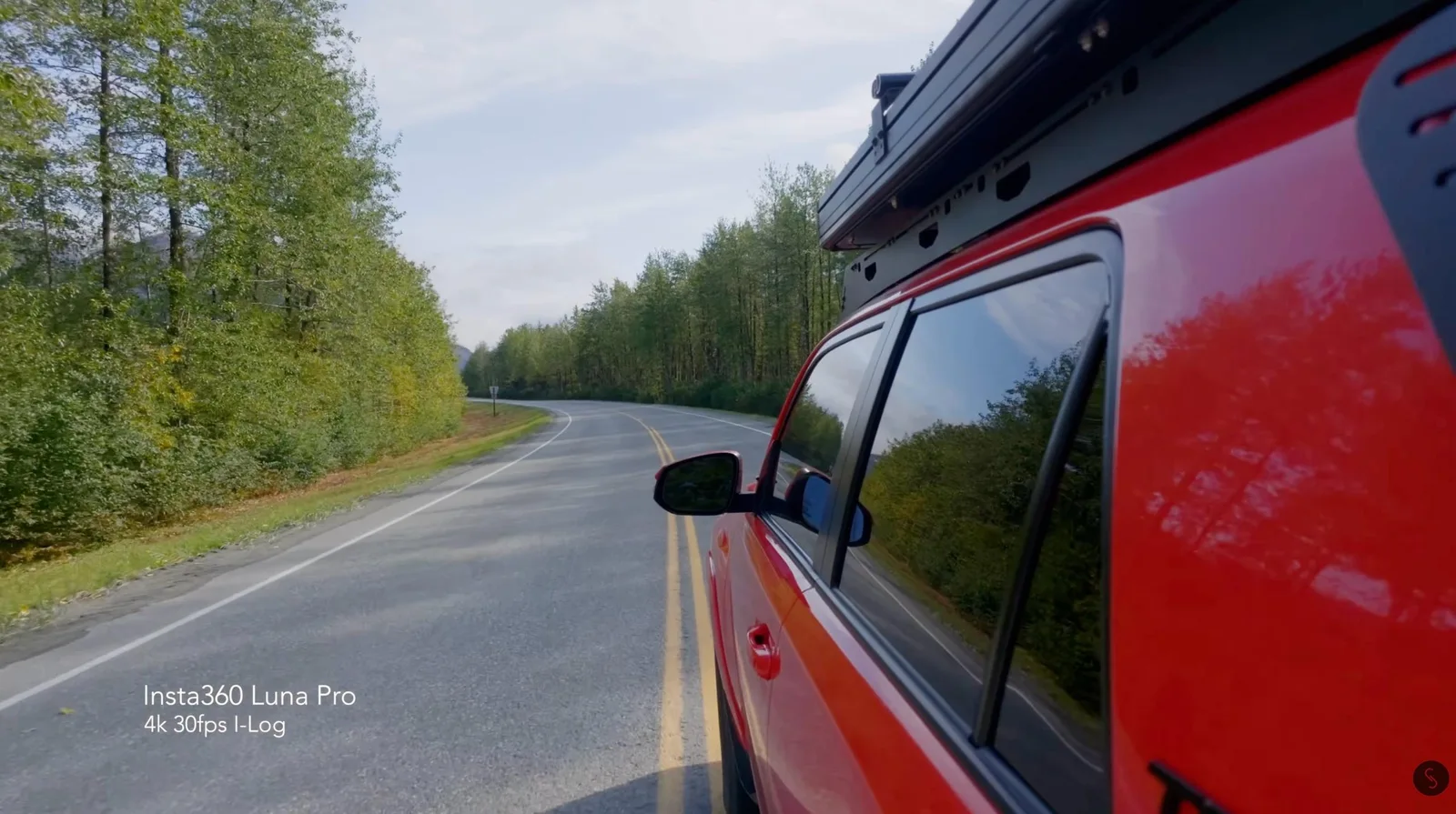 Insta360 Luna Pro camera mounted on a truck roof rack filming a forest-lined highway