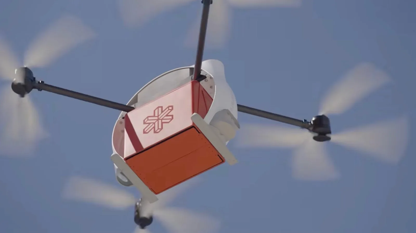 Close-up of Matternet's M3 delivery drone carrying its red cargo pod in flight