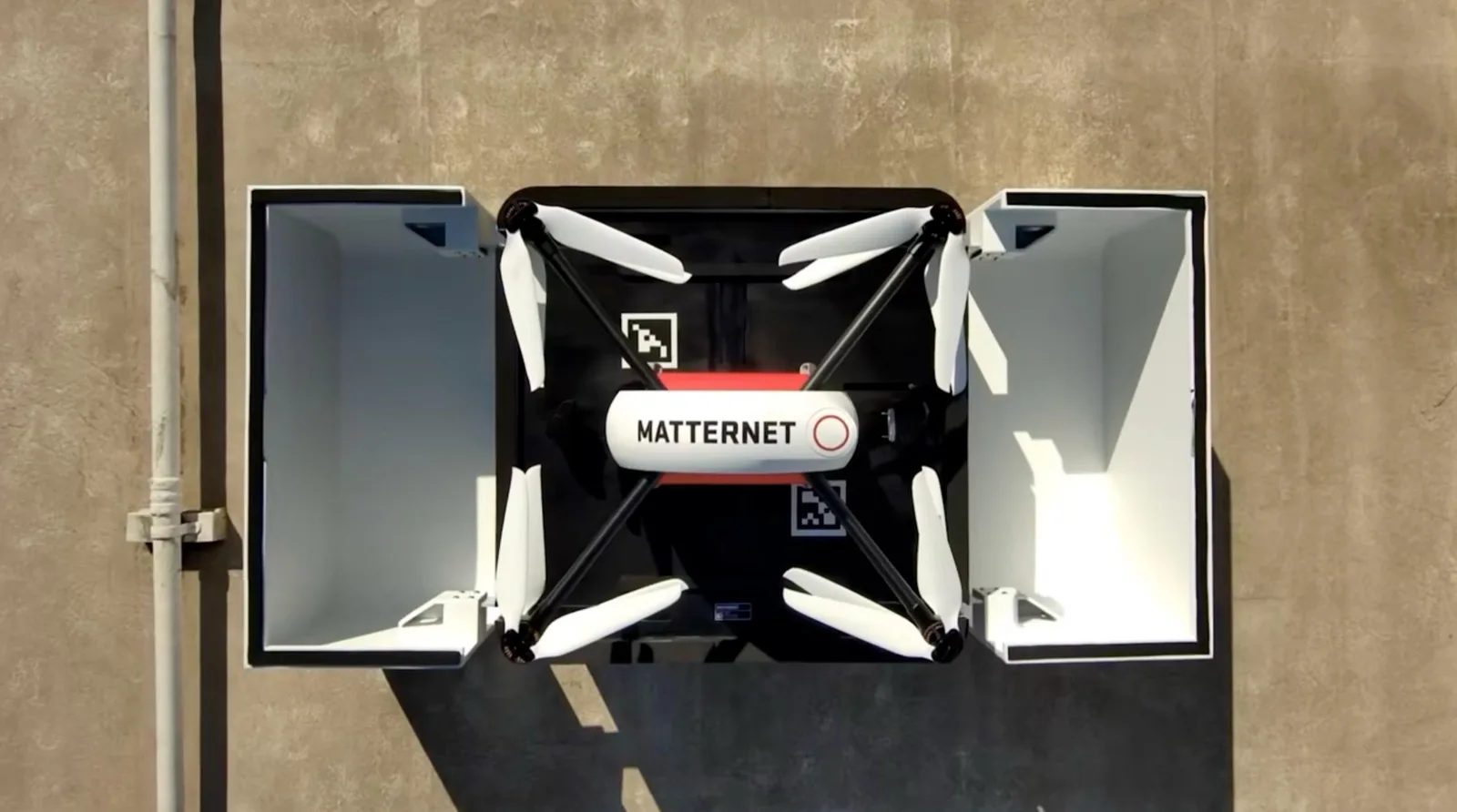 Top-down view of a Matternet M3 delivery drone resting inside an open rooftop dock