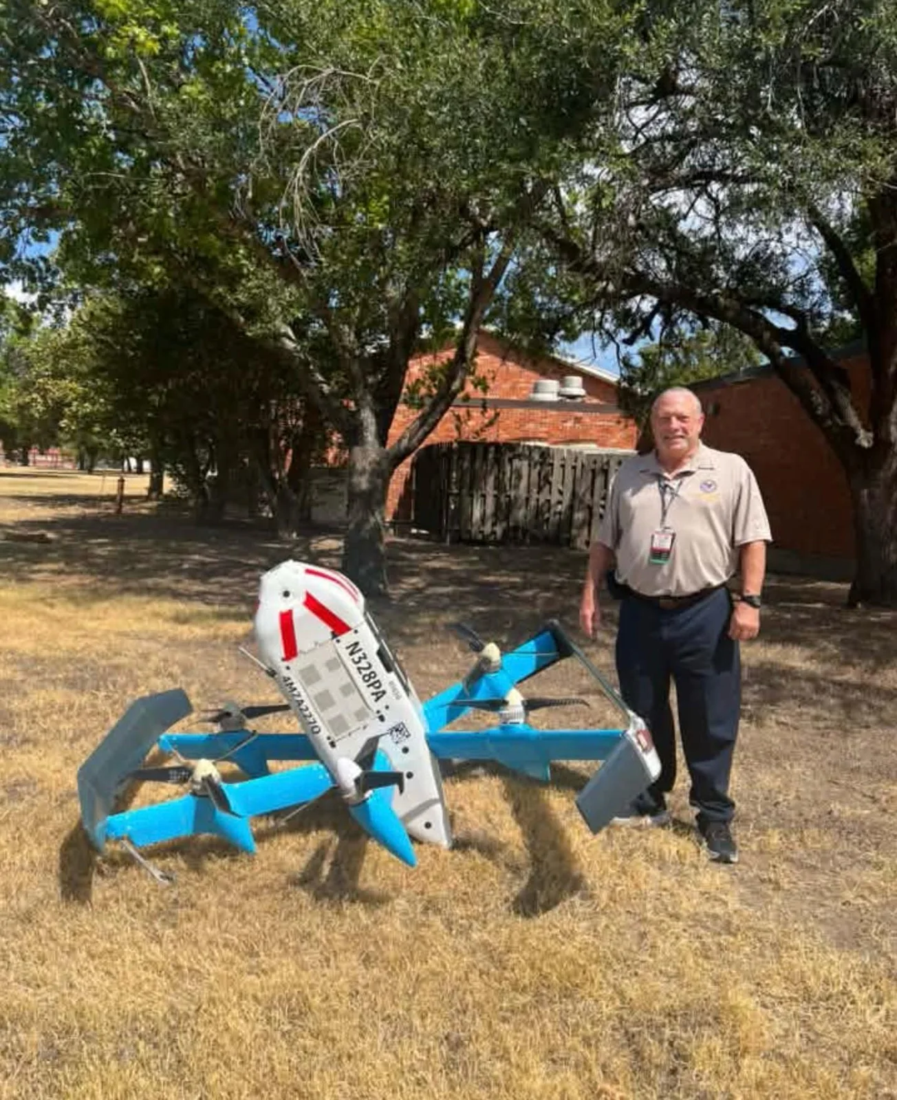 Man standing beside the Amazon MK30 drone N328PA for scale