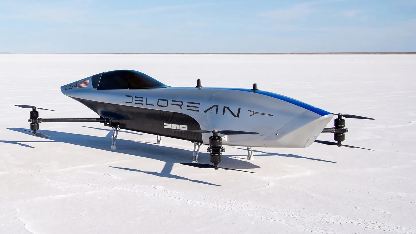 Silver Airspeeder Mk3C racing eVTOL with DeLorean and DMC lettering, a blue stripe and a USA flag, parked on a white salt flat