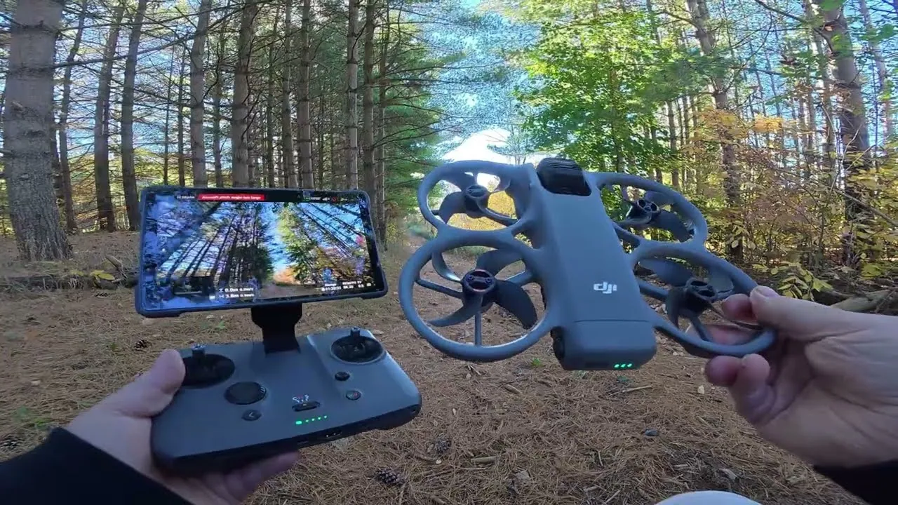 Hands holding a DJI RC Pro 2 controller with its screen showing the Avata 360 camera view, next to a DJI Avata 360 drone on a pine forest trail