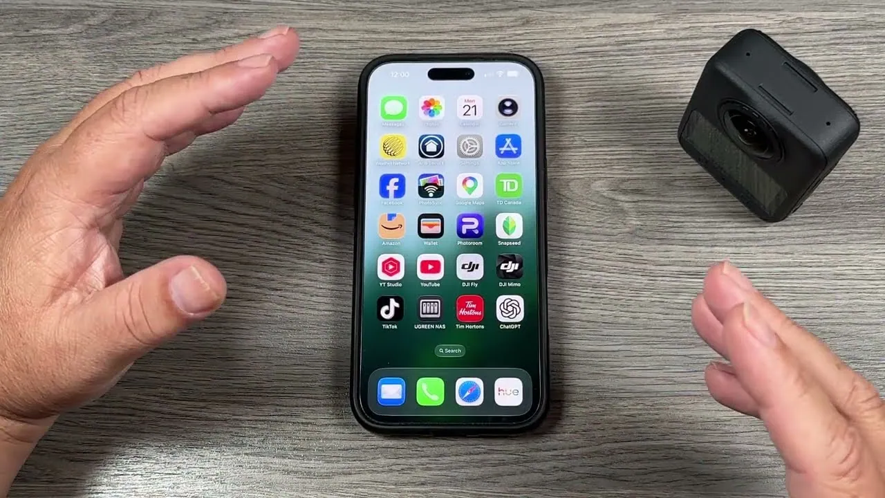An iPhone home screen with the DJI Mimo app icon, lying on a desk next to the DJI Osmo 360 II.