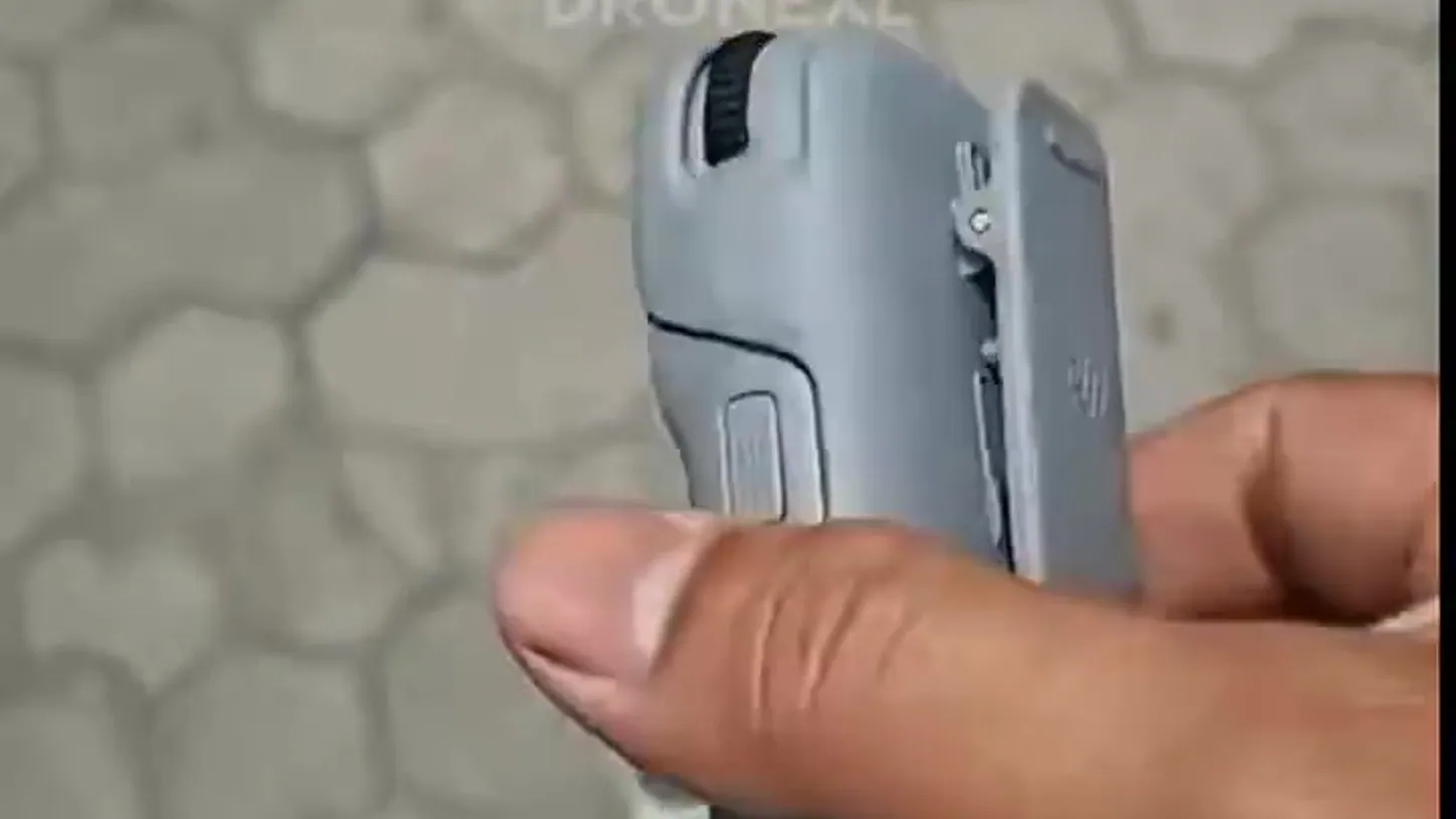Underside of the grey DJI RC Mini controller showing a ribbed scroll wheel, a sliding port cover and a hinged side clip