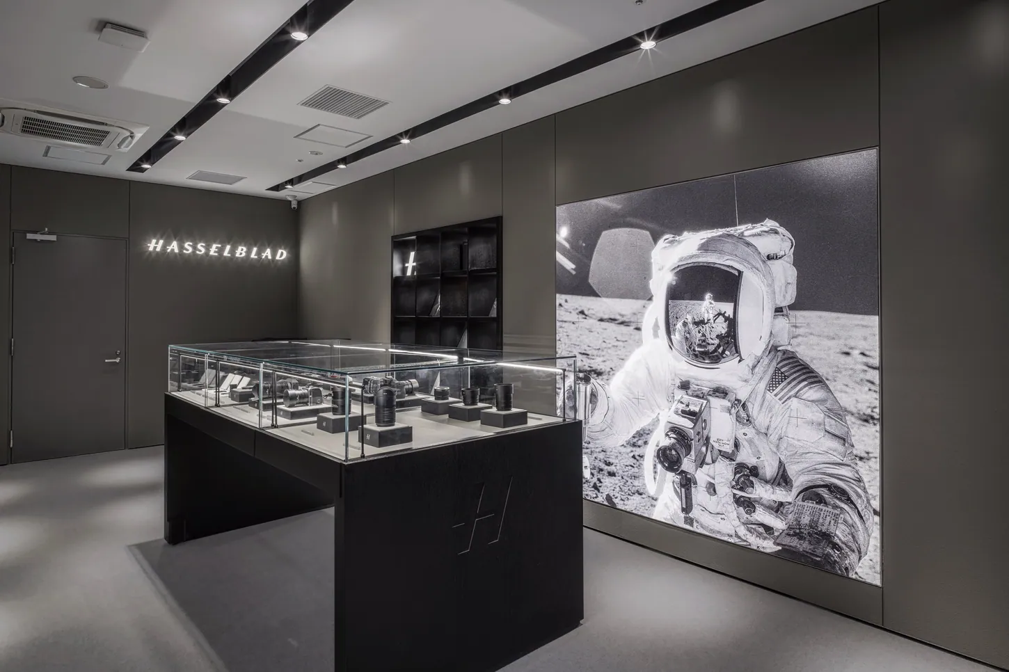 Hasselblad floor of the Tokyo store, a glass case of cameras and lenses in front of a large backlit print of an Apollo astronaut on the Moon with a camera on his chest