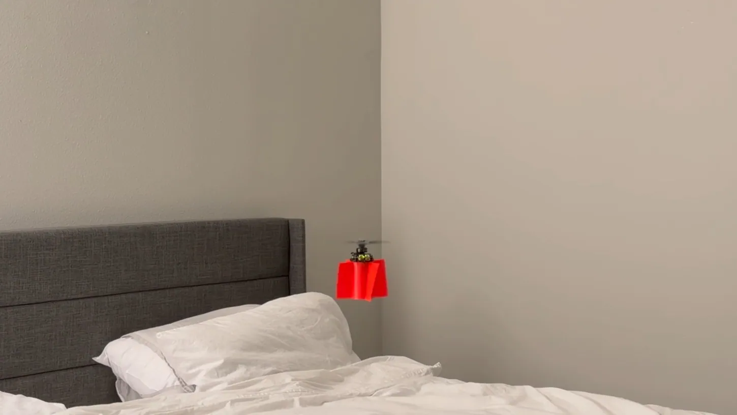Red single-motor drone hovering above a bed next to a bedroom wall