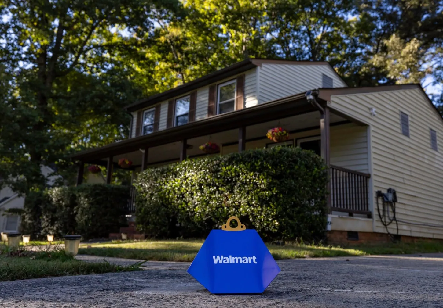 Blue Walmart drone delivery box sitting on a driveway in front of a two-story house with a covered porch