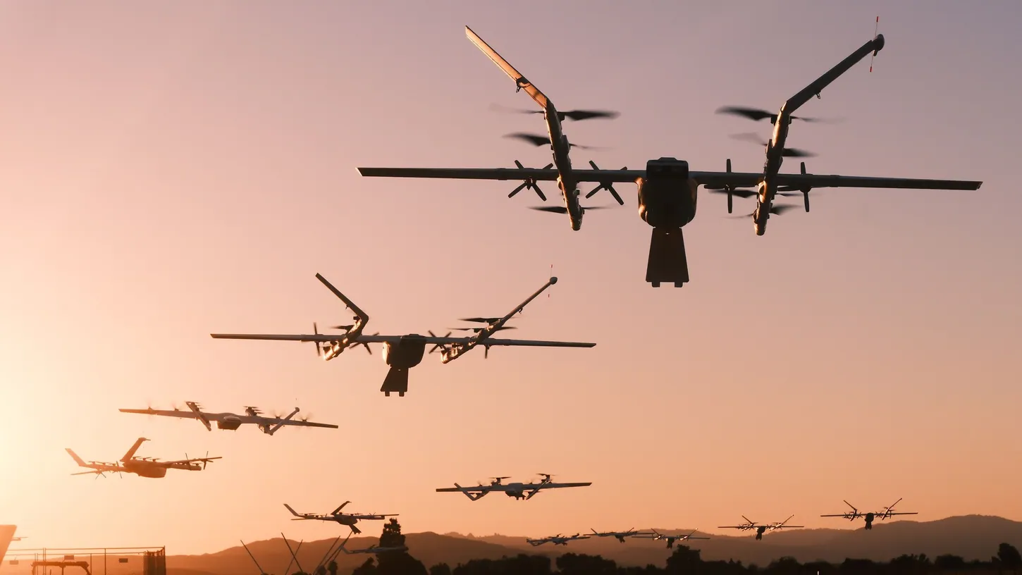 More than a dozen Wing delivery drones in the air at sunset over a test field, silhouetted against an orange sky